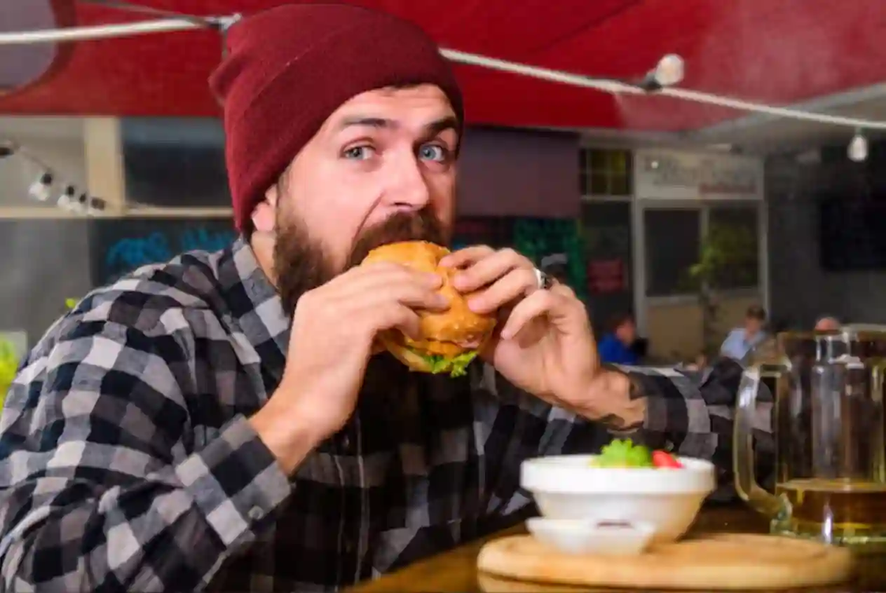 A man with red beanie eating a Boaty Delux Burger at the Boathouse Sports Bar & Grill in Mandurah WA